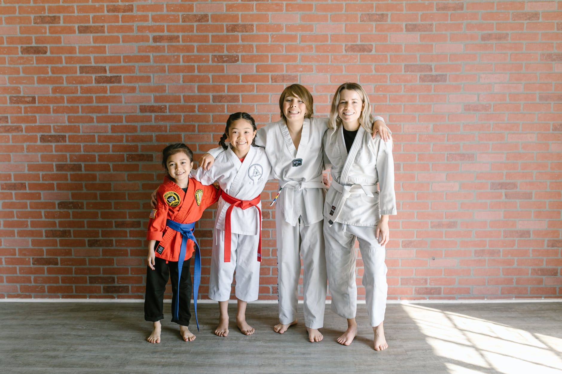 a group of people in taekwondo uniform standing near the wall barefooted