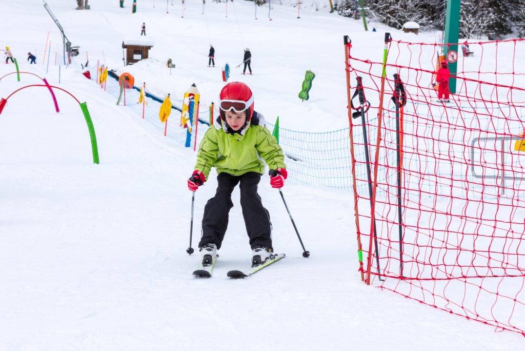 Little boy practicing skiing on ski lesson
