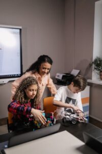 woman standing behind a girl and boy holding robots